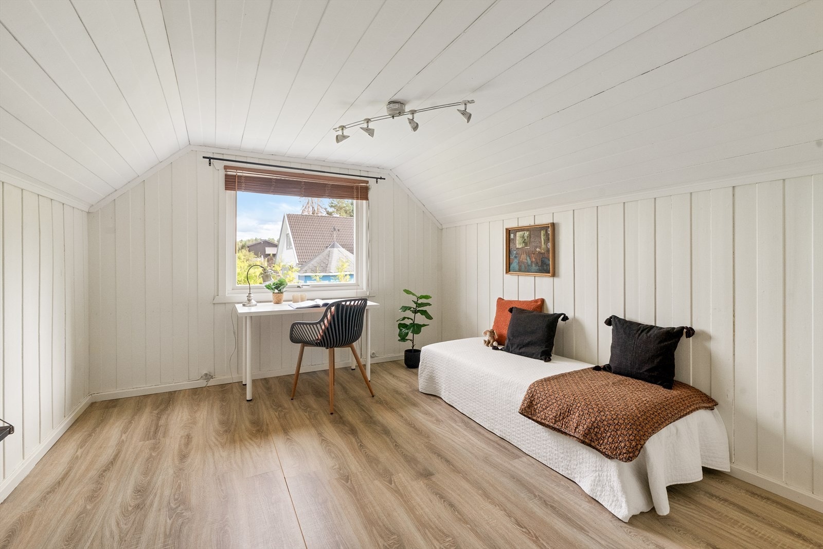 Et av to soverom i loftsetasjen, med skråtak og malt panel. Galleribilde