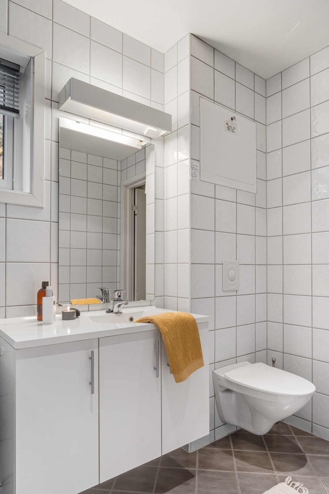 Badet er utstyrt med veggmontert toalett og servant i innredning. Galleribilde