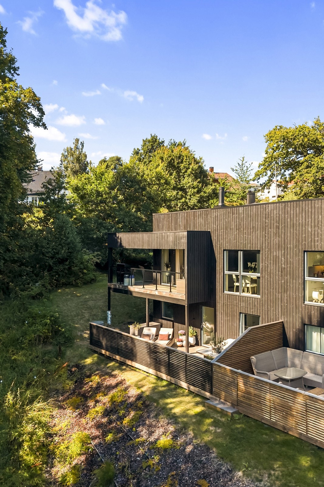 Tomten er skrånende med gruset gårdsplass og gressplen. Galleribilde