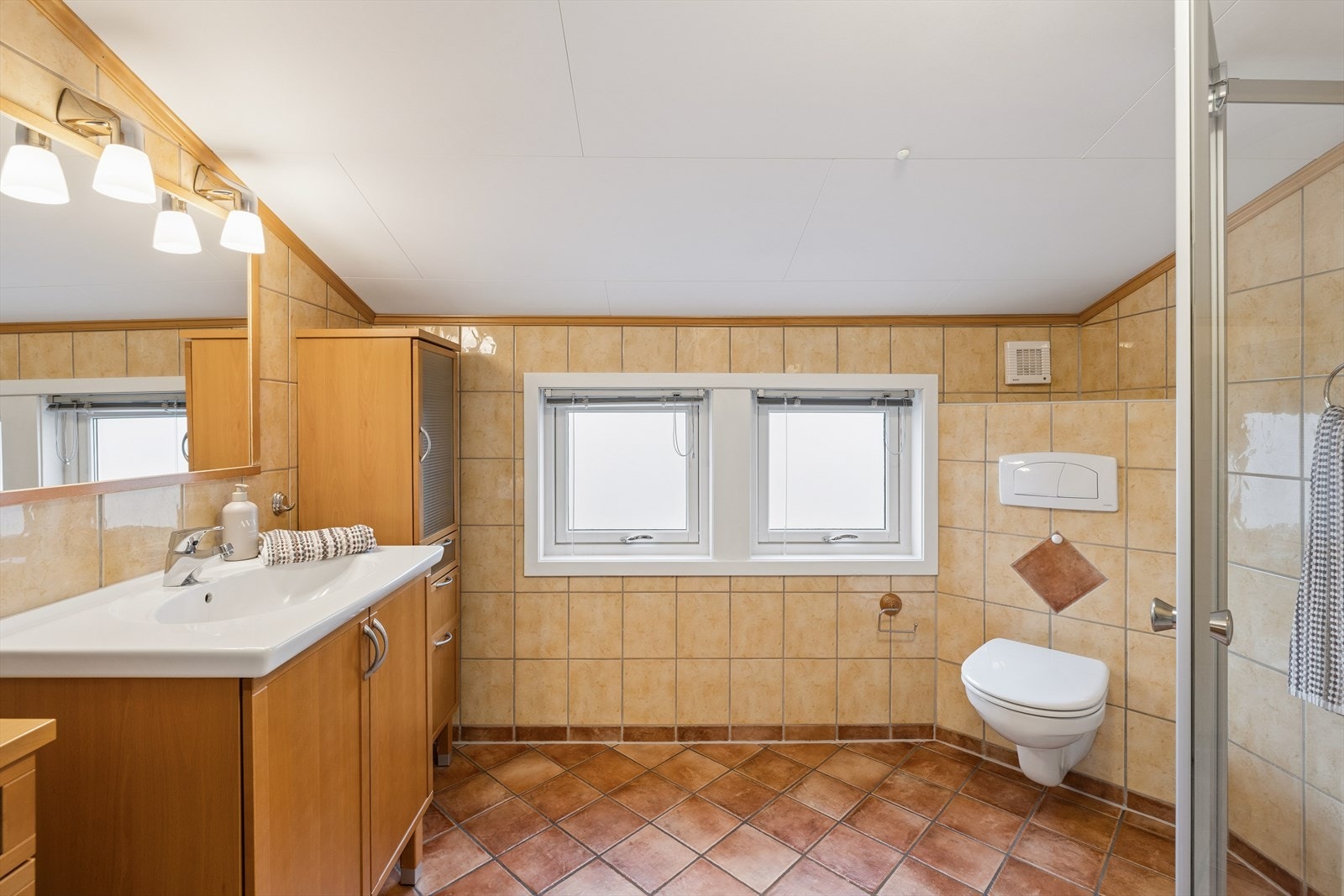 Badet i loftsetasjen har flislagte vegger og gulv med gulvvarme, samt himlingsplater i taket. Galleribilde