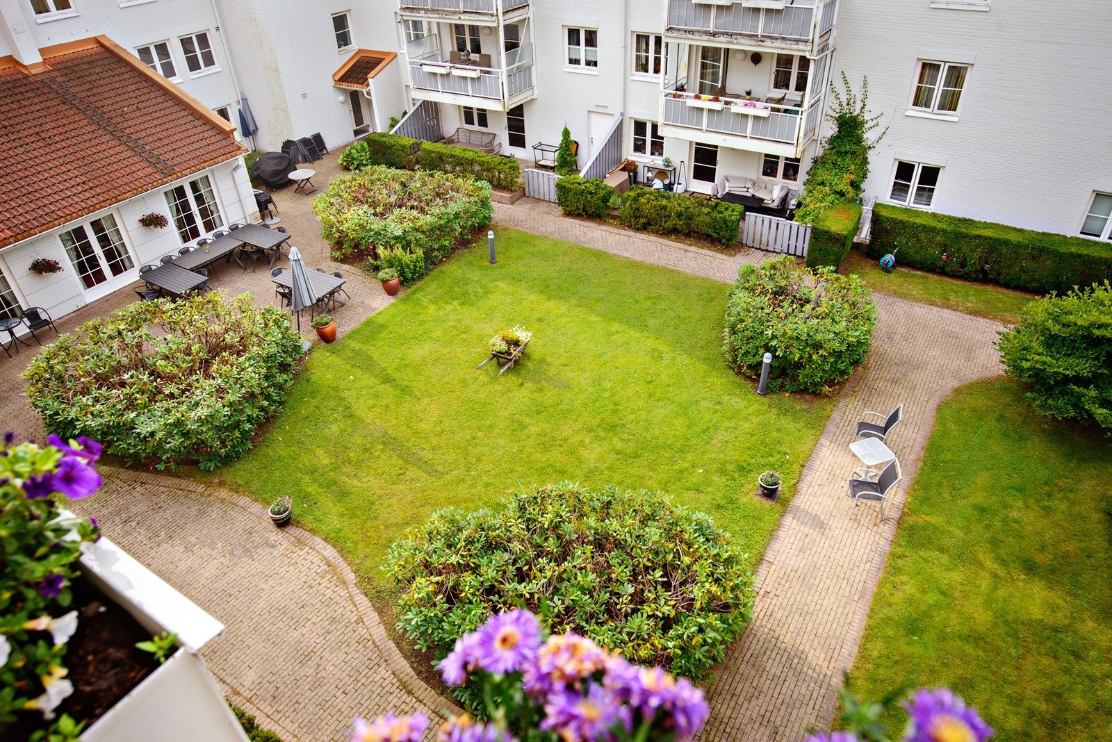Lys og oppgradert seniorleilighet med garasjeplass og vestvendt balkong mot sameiets flotte, felles atriumshage Galleribilde