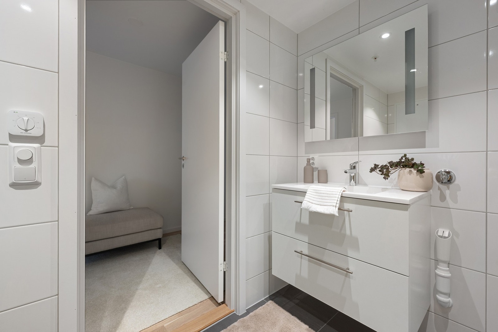 Badet har gulvvarme og downlights, og er innredet med vegghengt WC samt et 80 cm bredt servantskap med glatte, hvite skuffefronter og servant i hvit kompositt. Galleribilde