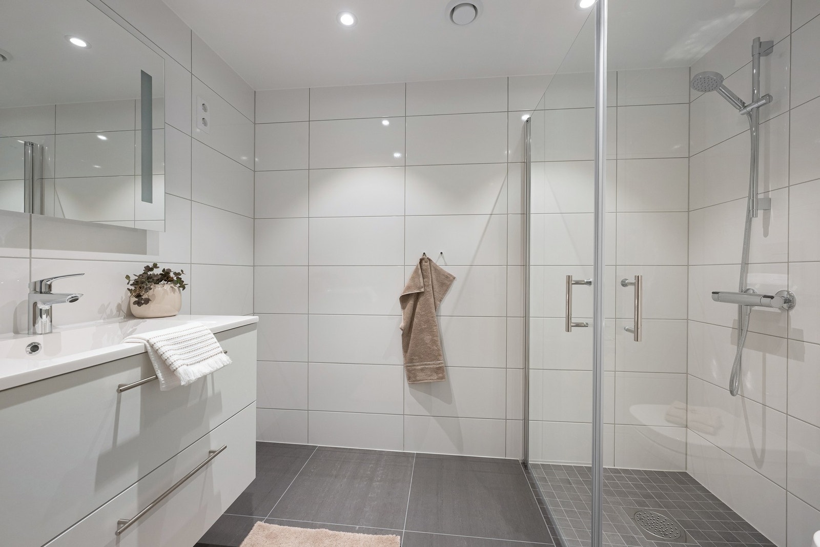 Badet har en moderne utførelse med grå 60 x 60 cm gulvfliser og hvite 60 x 30 cm fliser på veggene. Galleribilde