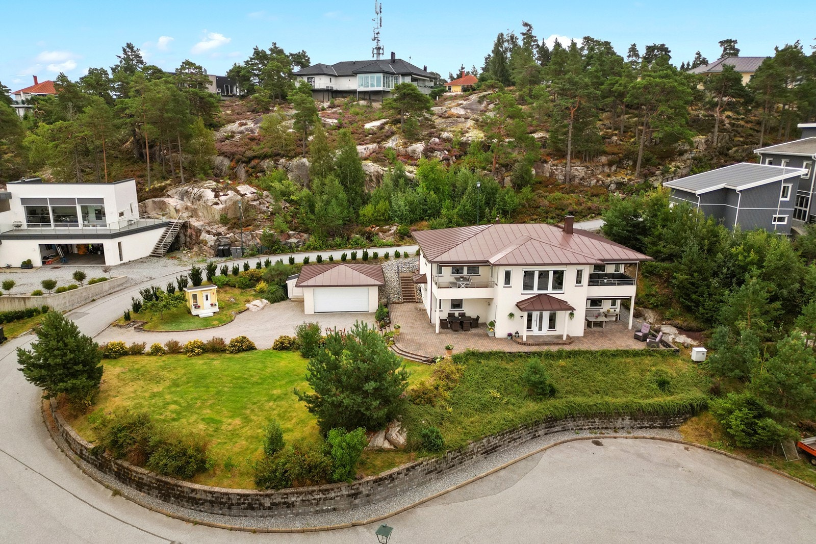 Tomten grenser mot naturlig skogsterreng med synlig fjell i dagen. Galleribilde