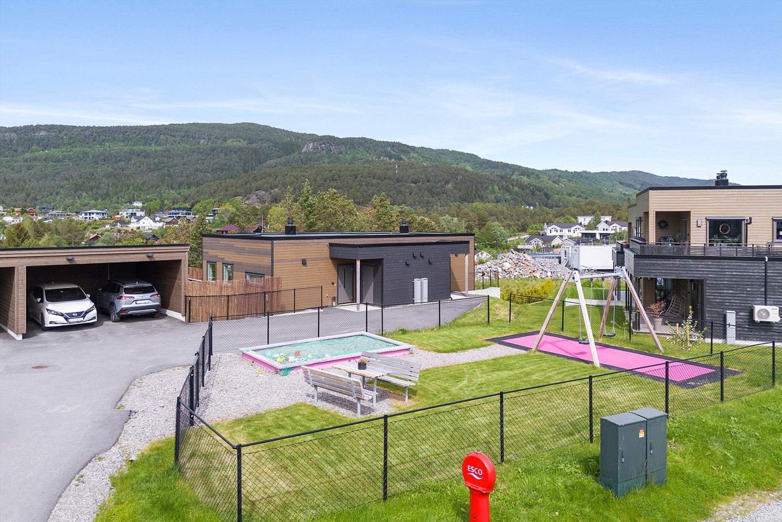 Området bak boligen er pent opparbeidet med asfaltert tilkomst, carport og lekeplass Galleribilde
