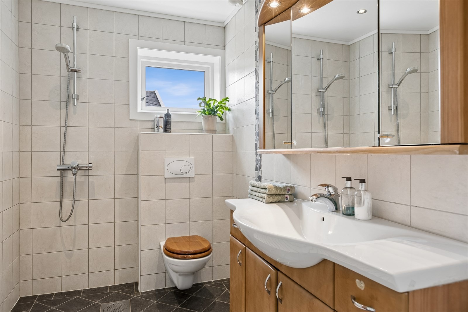 Badet i 1. etasje ble totalrenovert i 2005 og fremstår som et funksjonelt og innbydende våtrom. Rommet er innredet med flislagt gulv med behagelig gulvvarme, flislagte vegger og malte himlingsplater med integrerte downlights. Galleribilde
