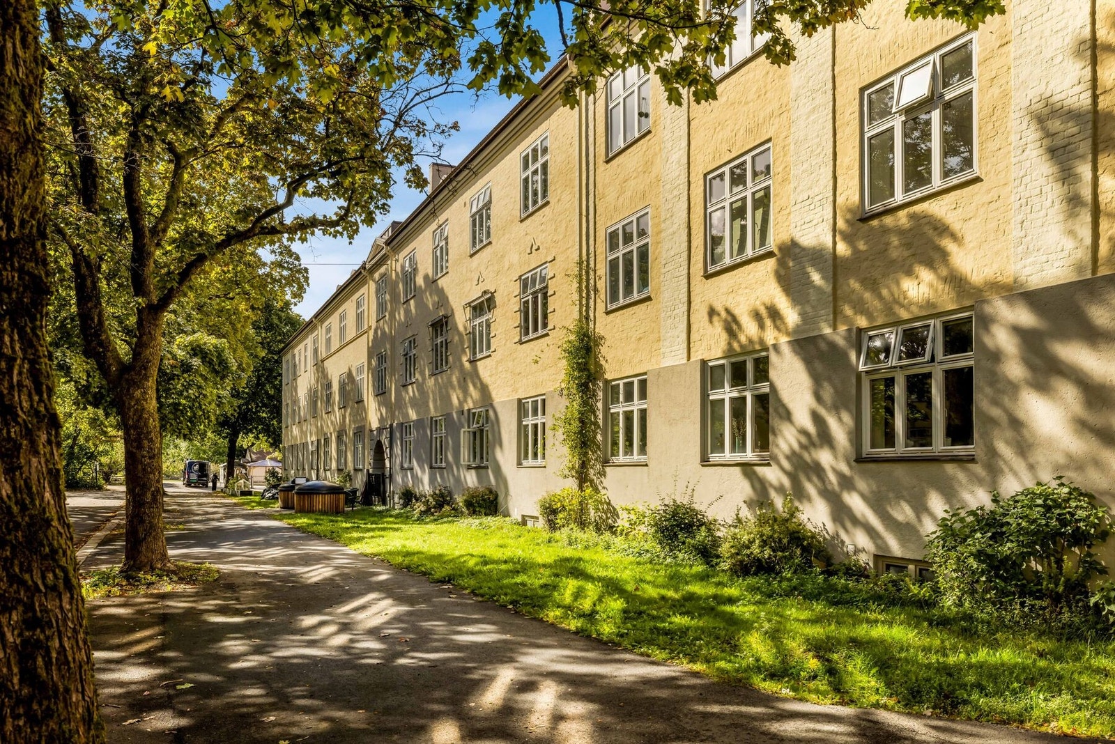 Bygningen ligger tilbaketrukket fra fortau og adkomstveier med mellomliggende forhage / plenarealer. Galleribilde