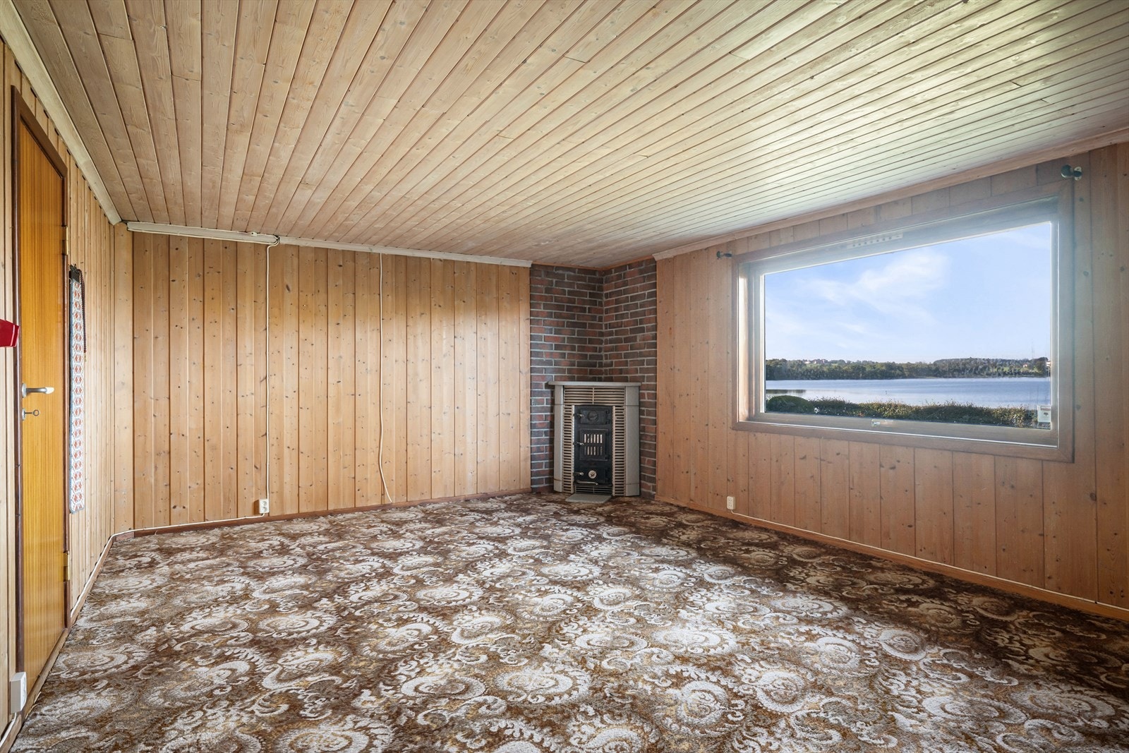 Romslig kjellerstue (ikke godkjent) med teppebelagt gulv og panelvegger. Galleribilde