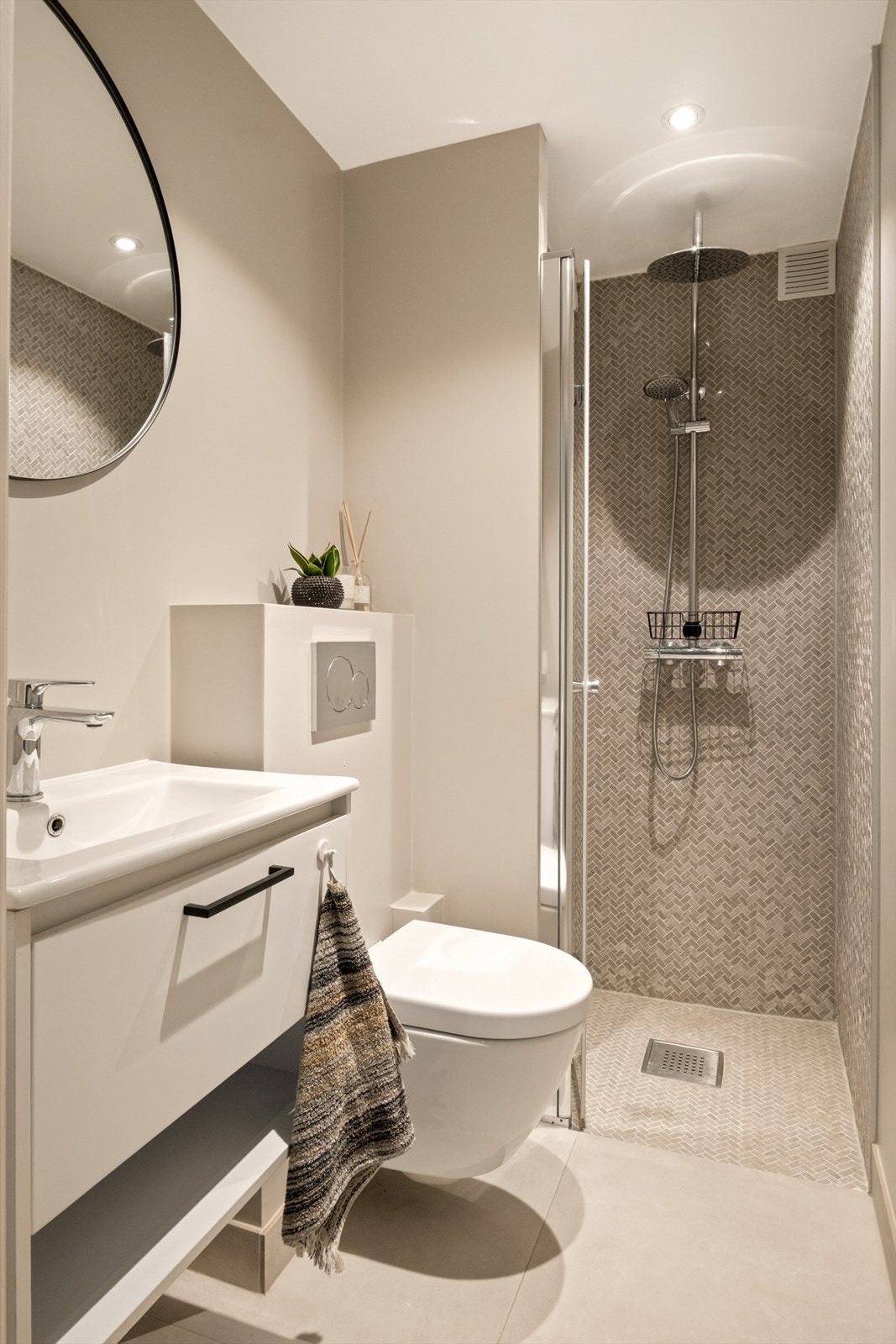 Moderne og delikat baderom fra 2022 med flislagte vegger og gulv, malt tak og varmekabler. Badet er innredet med benkeskap med slette fronter, servant i helstøpt plate og speil Galleribilde