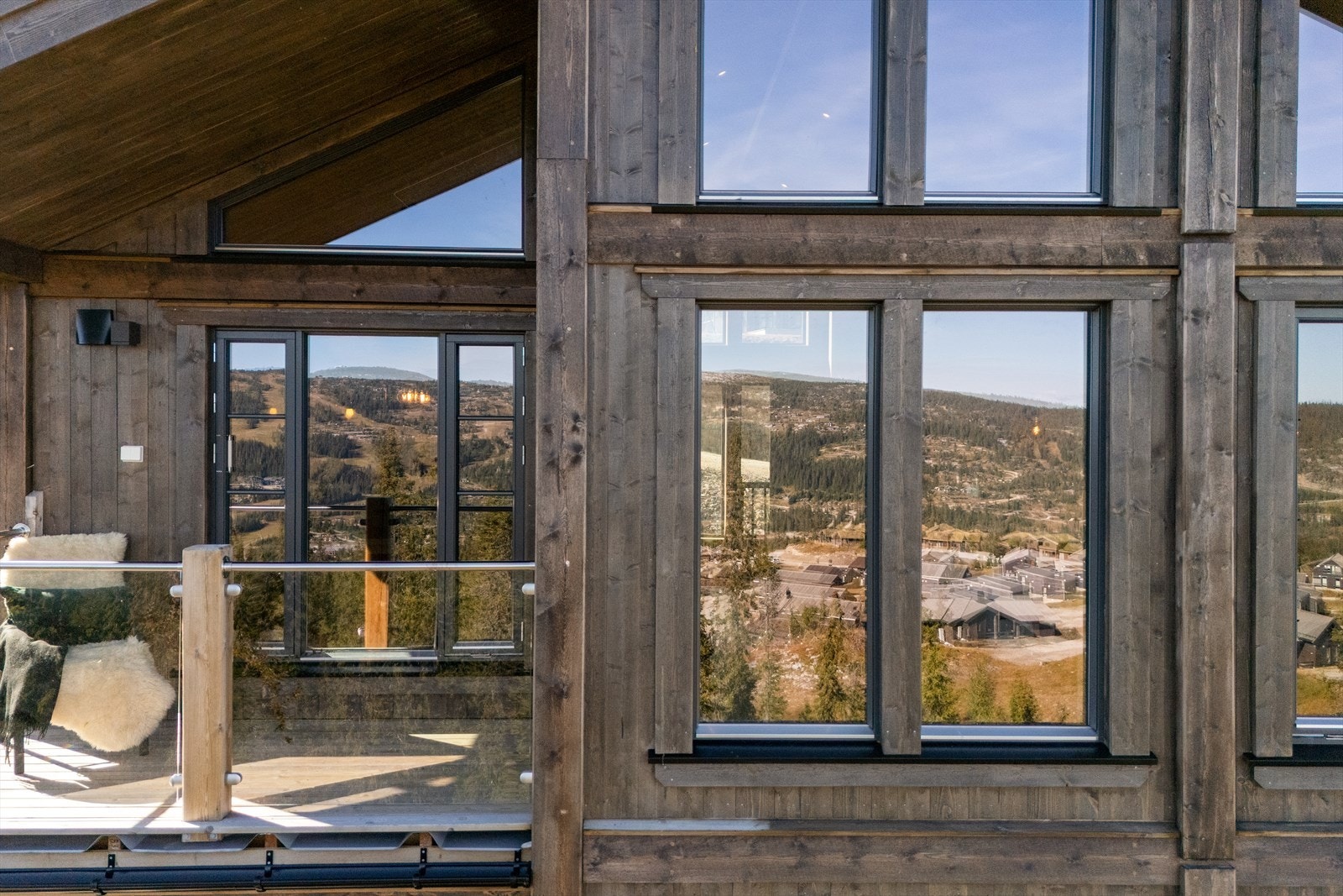 Store glassflater reflekterer det åpne fjellterrenget. Galleribilde