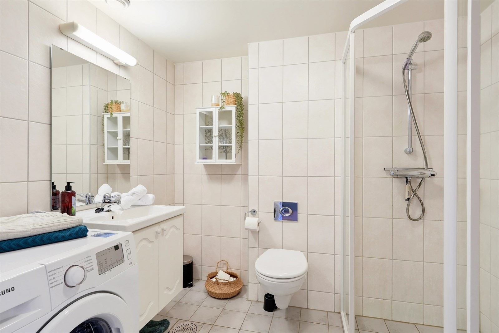 Badet er utstyrt med vegghengt toalett, dusj med skyvedører, samt baderomsinnredning med servant og speil. Galleribilde