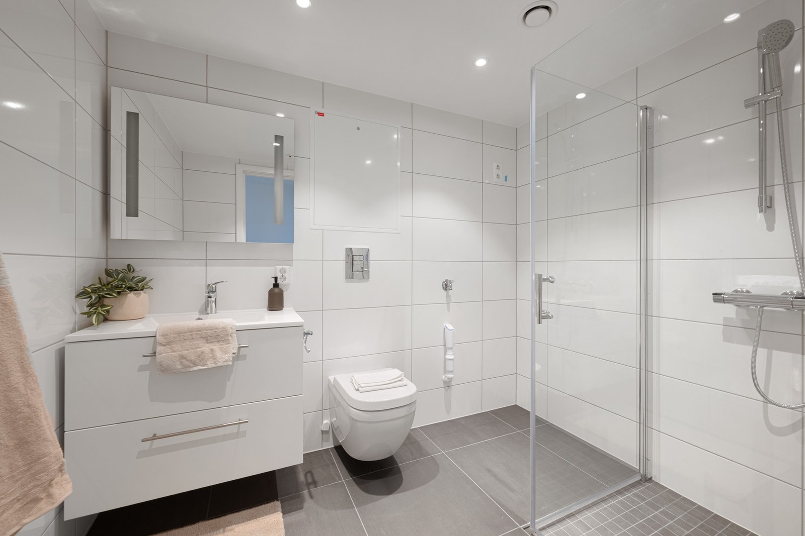 Badet har gulvvarme og downlights, og er innredet med vegghengt WC samt et 80 cm bredt servantskap med glatte, hvite skuffefronter og servant i hvit kompositt. Armaturene er fra Mora og Grohe. Galleribilde