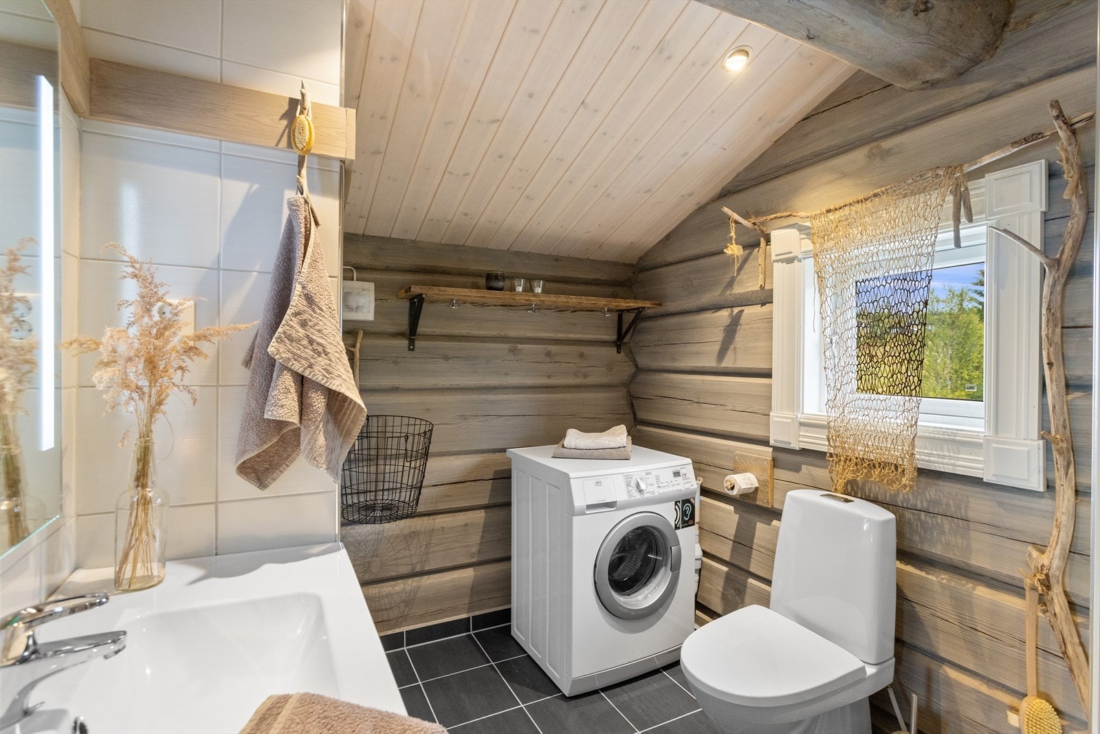 Badet i andre etasje har tømmervegger, flislagt gulv med varme og opplegg for vaskemaskin. Galleribilde