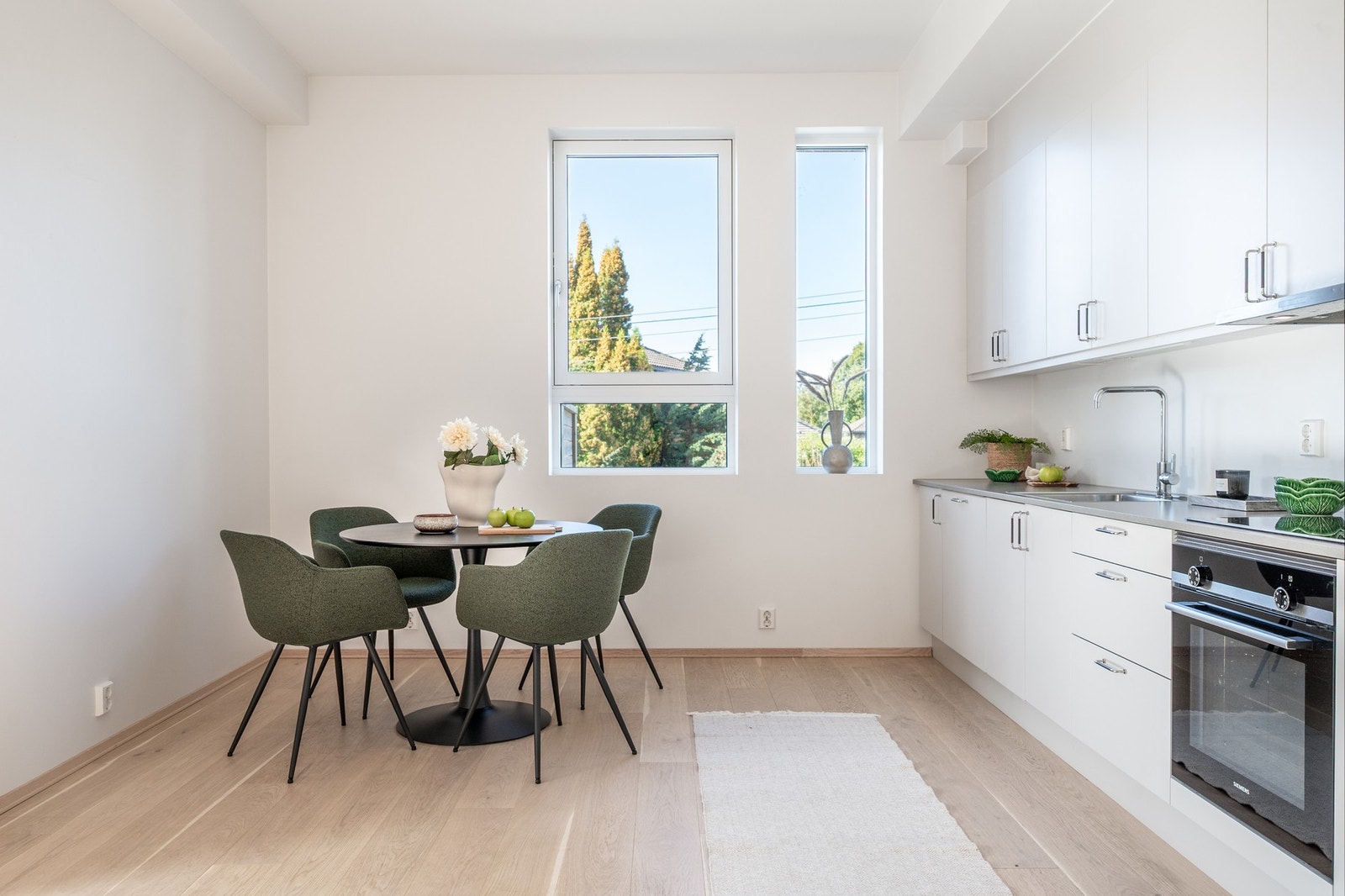 Innredningen har hvite, profilerte fronter med metallhåndtak og en lys benkeplate. Galleribilde