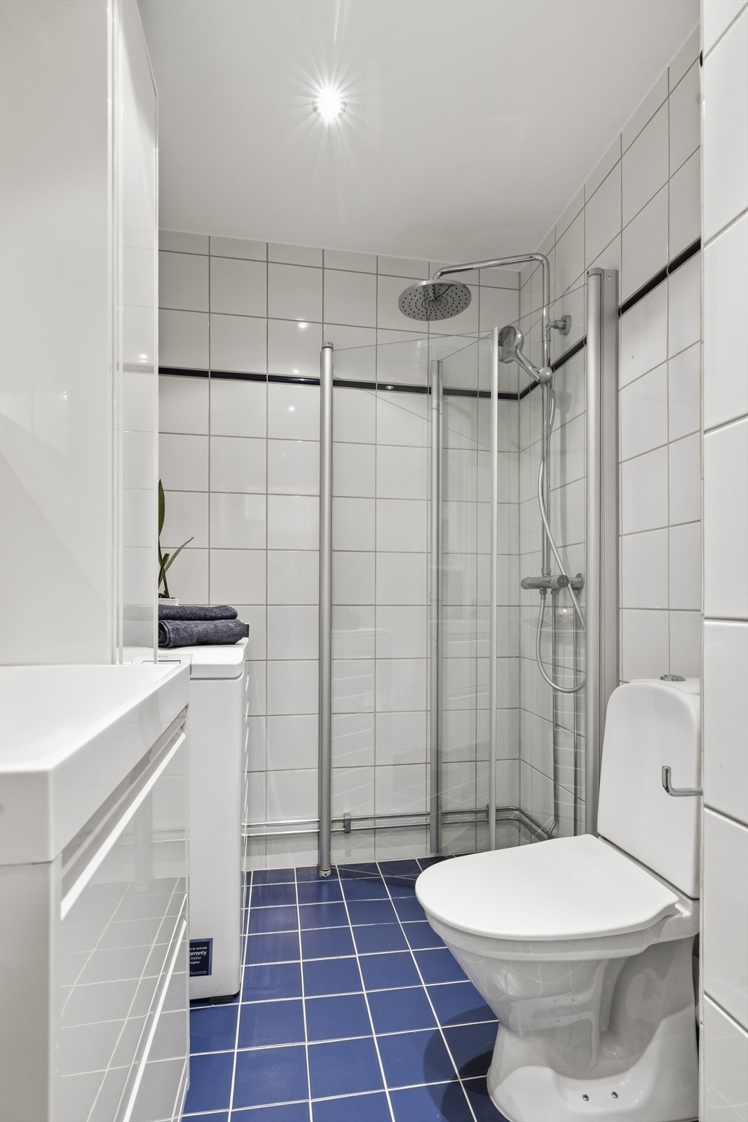 Flislagt baderom med gulvvarme, moderne downlights og opplegg for vaskemaskin Galleribilde