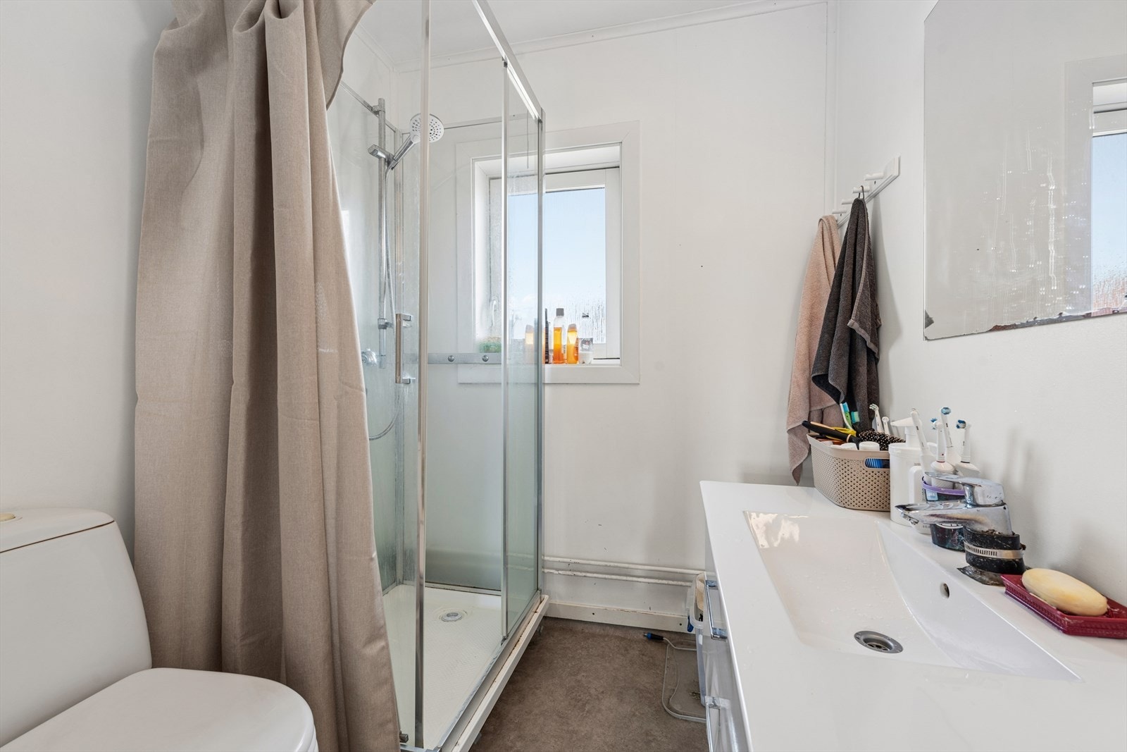Badet er av eldre dato og har behov for modernisering. Rommet er innredet med skap med glatte fronter, servant, gulvstående klosett og dusjkabinett. Galleribilde