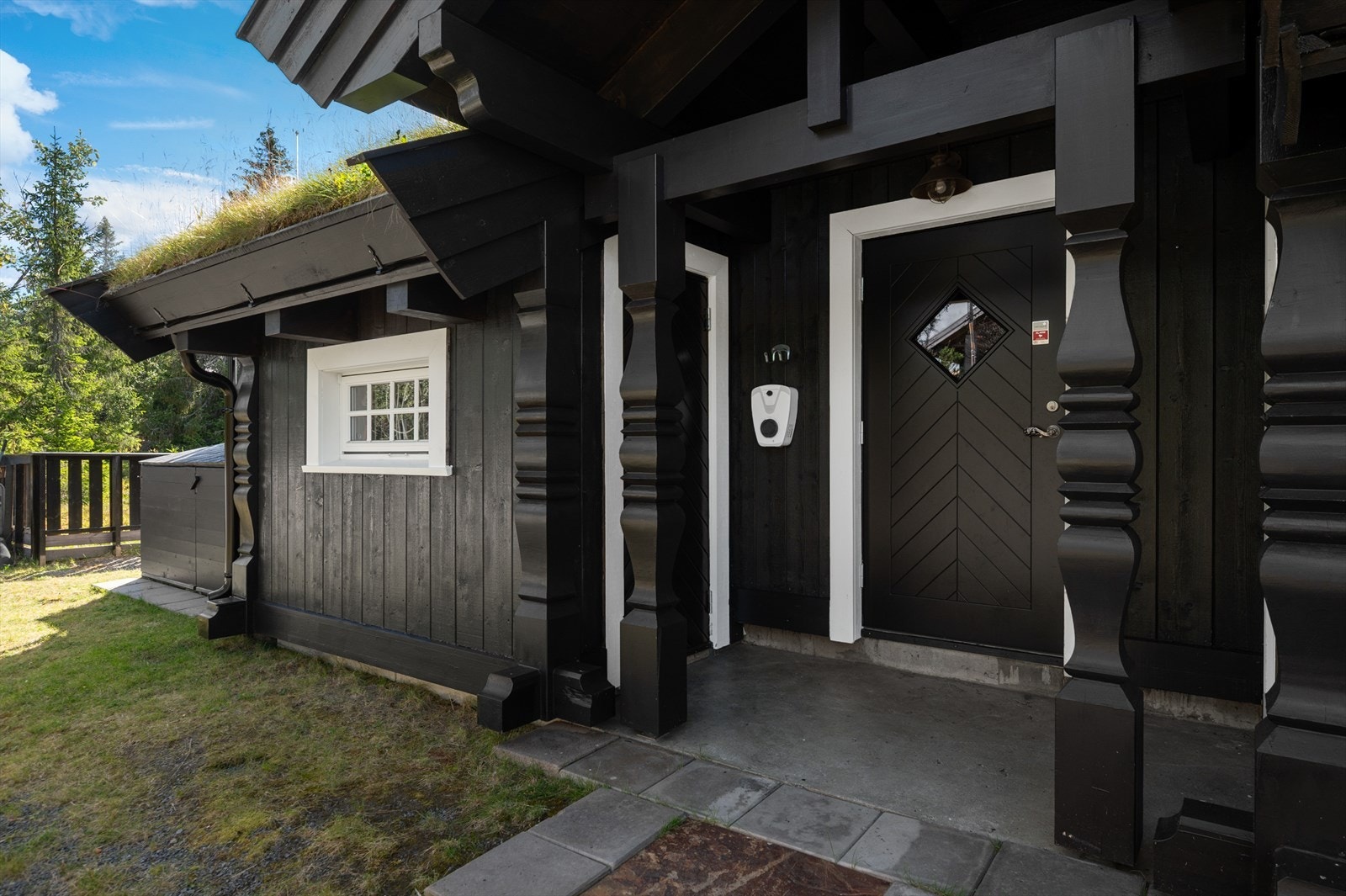 Du ønskes velkommen inn via et flott overbygget inngangsparti med støpt terrasse. Her det adkomst til 2 praktiske boder på totalt 6m². Det er også montert elbil-lader. Galleribilde