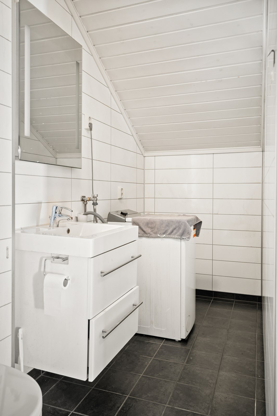 Servant med baderomsinnredning, speil med integrert belysning og opplegg for vaskemaskin. Galleribilde