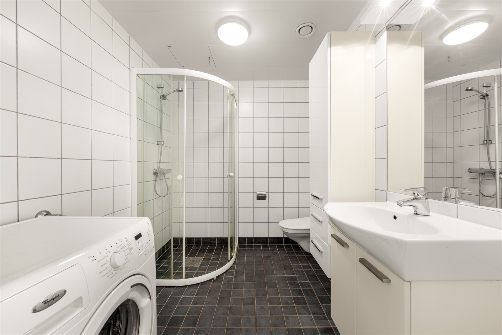 Pent og funksjonelt bad med flislagte vegger og gulv, samt behagelig gulvvarme. Dusjsone med vegger i herdet glass, og opplegg for vaskemaskin. Galleribilde