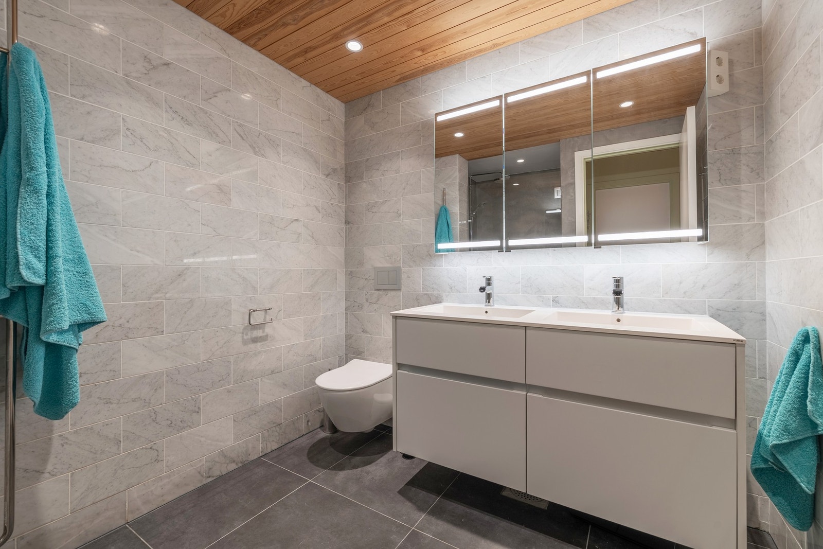 Badet har flislagt gulv med elektriske varmekabler, samt flislagte vegger som er kombinert med microsement på én vegg i dusjhjørne. Galleribilde