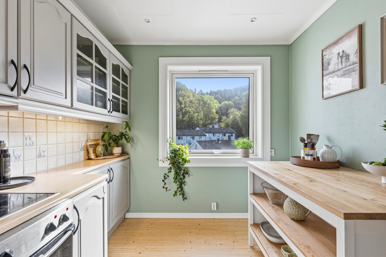 Kjøkkeninnredningen har profilerte fronter, laminert benkeplate, oppvaskkum, ventilator, fliser over benkeplaten og opplegg for oppvaskmaskin. Galleribilde