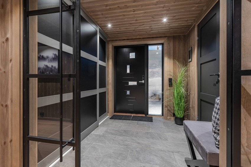 Velkommen inn! Entréen har fliser på gulv og skyvedørsgarderobe. Her finner vi også en Ipad med kontrollpanel for belysning i hele hytta. Galleribilde