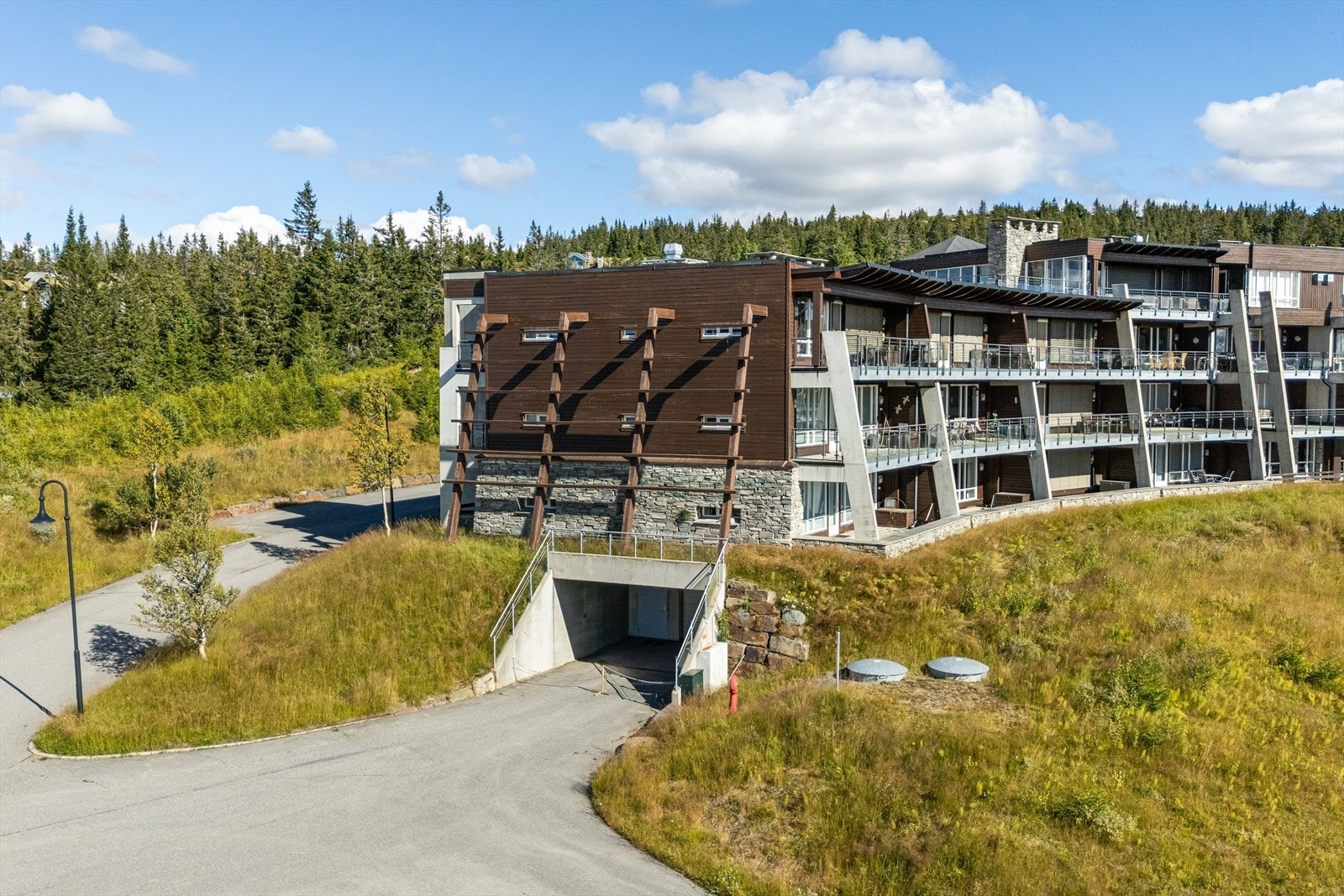 Fasader i trepanel og naturstein, med innkjøring direkte til garasjeanlegget. Galleribilde