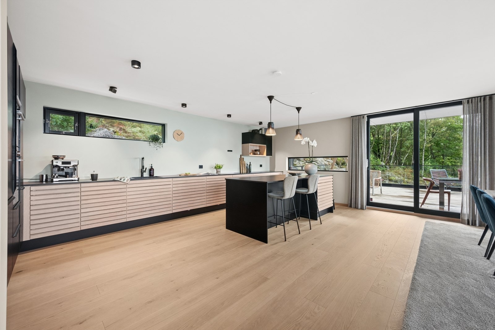 Kjøkkenet er levert av kvalitetsleverandøren HTH og er stilrent innredet med en kombinasjon av sorte og eikefargede fronter og en mørk og solid benkeplate i dekton. Galleribilde