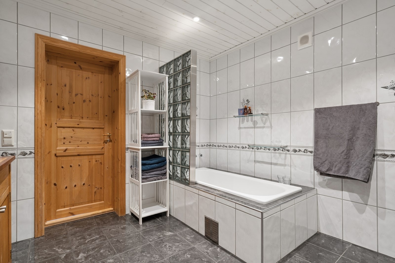 Badet har heldekkende fliser på gulv og vegger samt panel i himling. Galleribilde