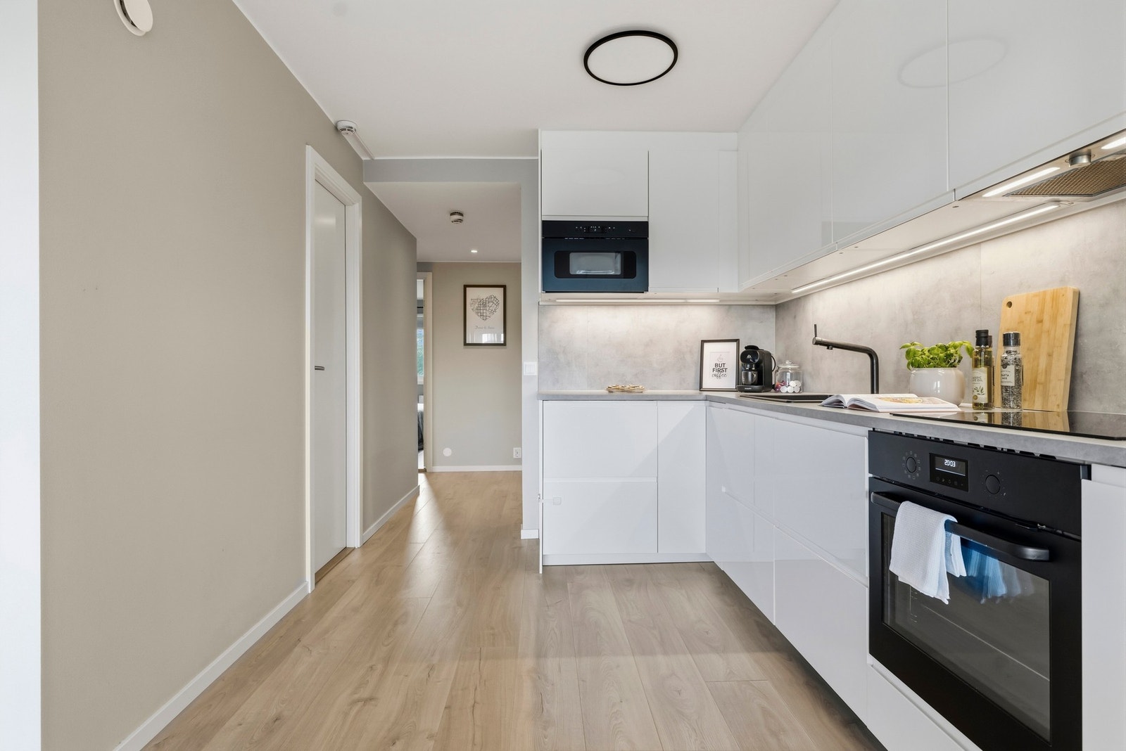 Pent IKEA kjøkkeninnredning med glatte høyglans skapfronter, laminat
benkeplate med sprutplate i samme utførelse, enkel oppvaskkum,
ventilator og innfelte hvitevarer som koketopp, stekeovn,
oppvaskmaskin, kjøl/- fryseskap Galleribilde