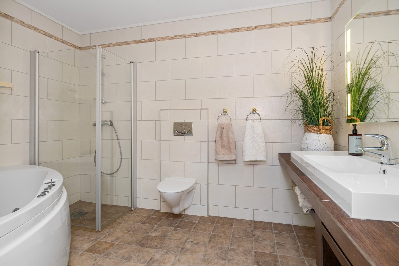 Badet er innredet med toalett, servant, dusjvegger og boblebad. Galleribilde
