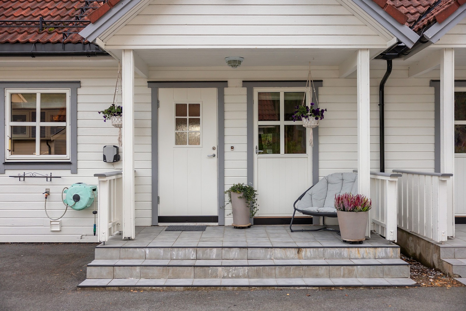 Overbygd inngangsparti med belysning og flislagt terrasse Galleribilde