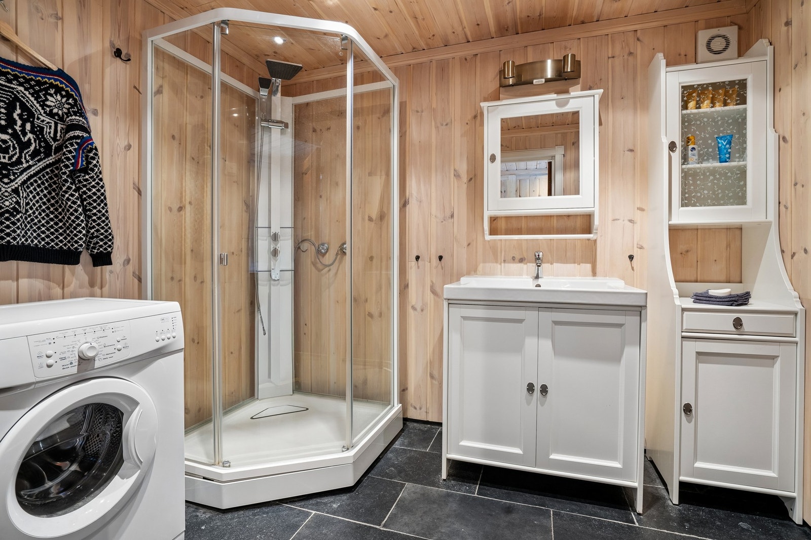 Badet har flislagt gulv og trepanel på vegger. Opplegg til vaskemaskin. Galleribilde