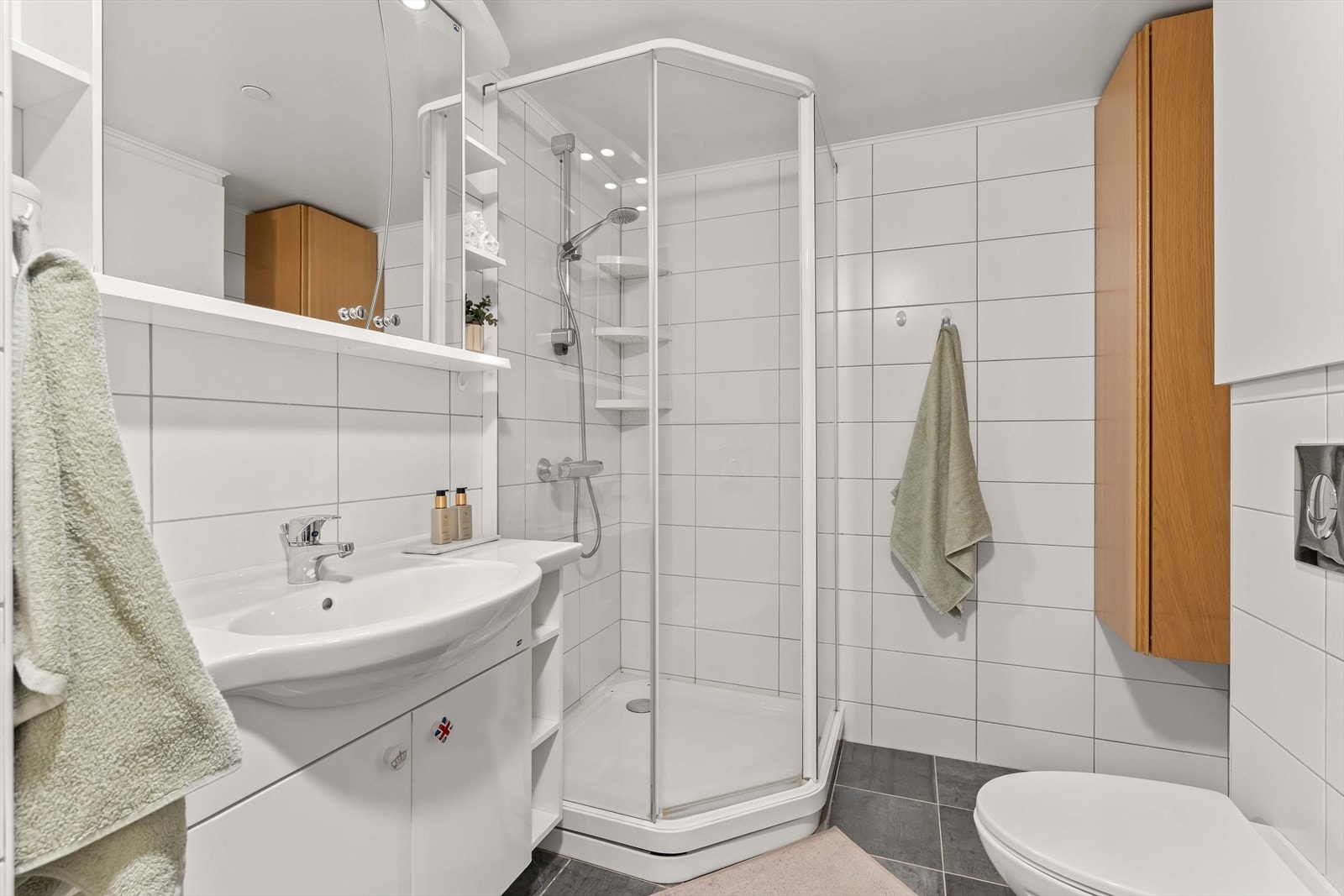 Badet er innredet med servant med oppbevaring, dusjkabinett og praktiske skapløsninger. Galleribilde