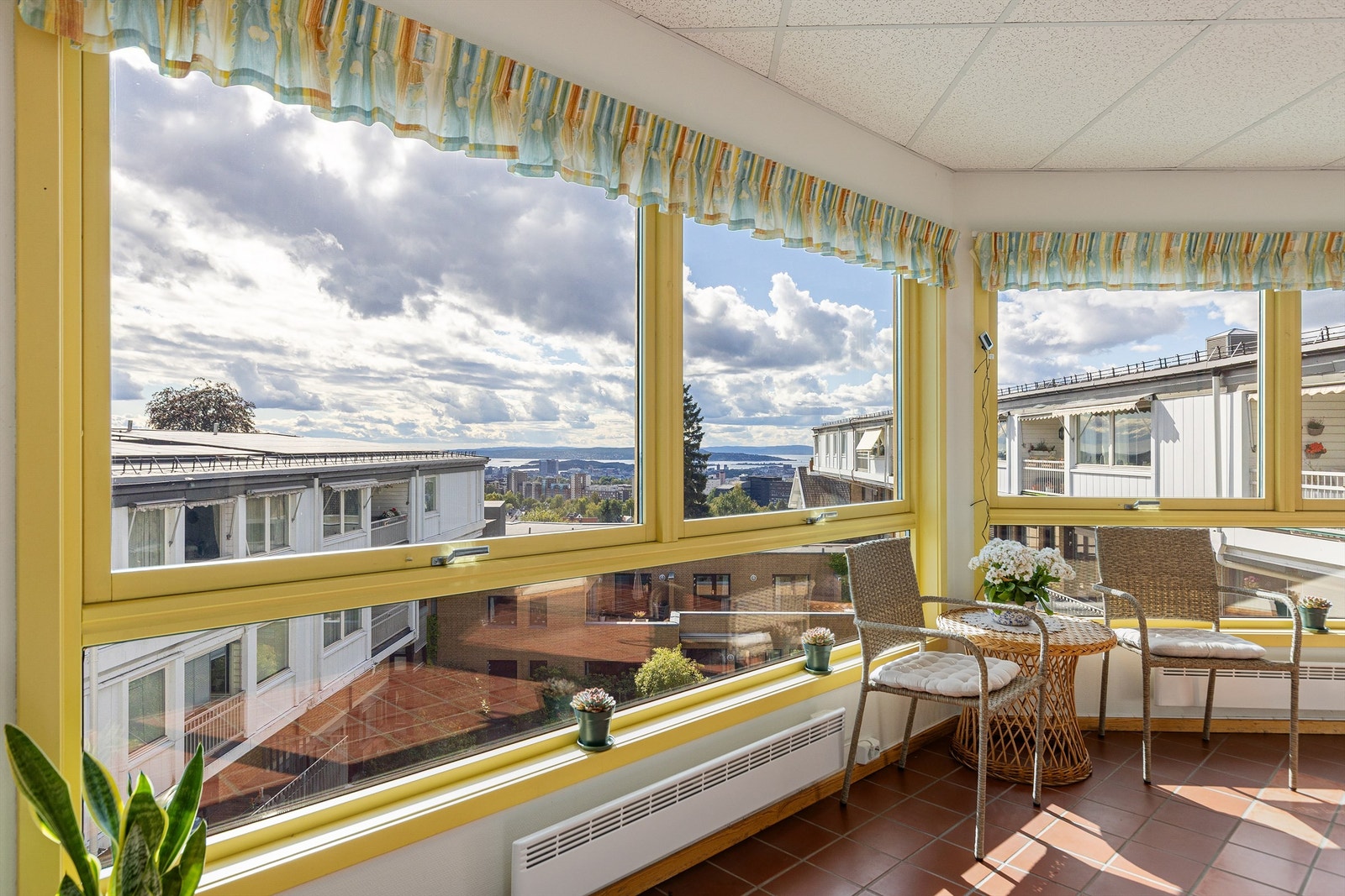 Felles innglasset oppholdsareal med sitteplasser og flott fjordutsikt. Galleribilde