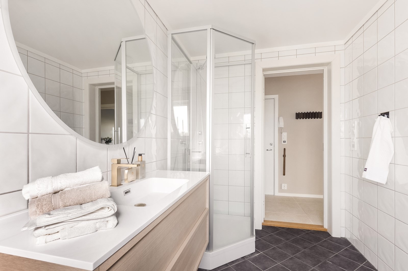 Badet er innredet med dusjkabinett med glassdører og helflisede overflater. Galleribilde
