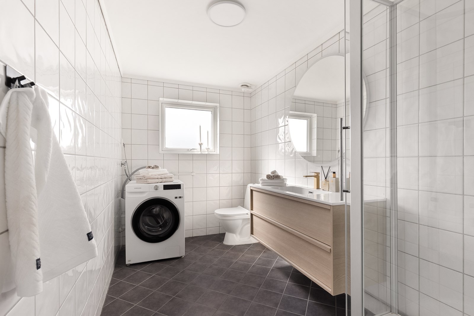 Badet har flislagte overflater med gulvvarme og opplegg for vaskemaskin. Galleribilde