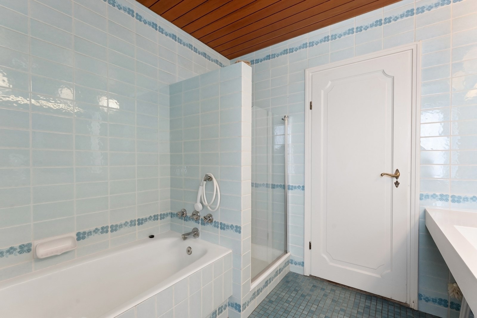 Badet har både badekar og dusjnisje. Flislagte overflater og himling med lakkert redwoodpanel. Galleribilde