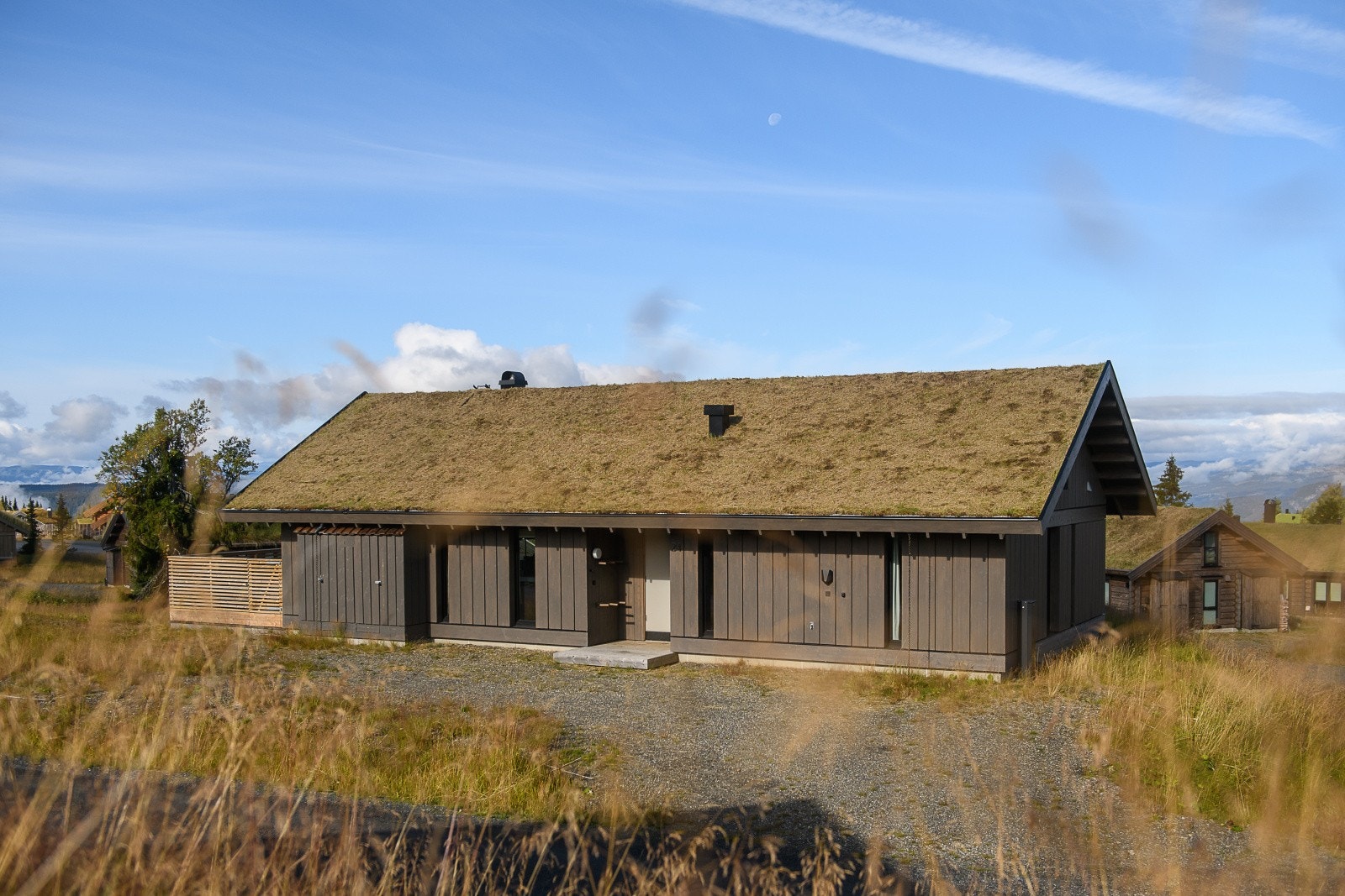 Fasaden har stående mørk trekledning og torvtak som glir harmonisk inn i fjellnaturen. Galleribilde