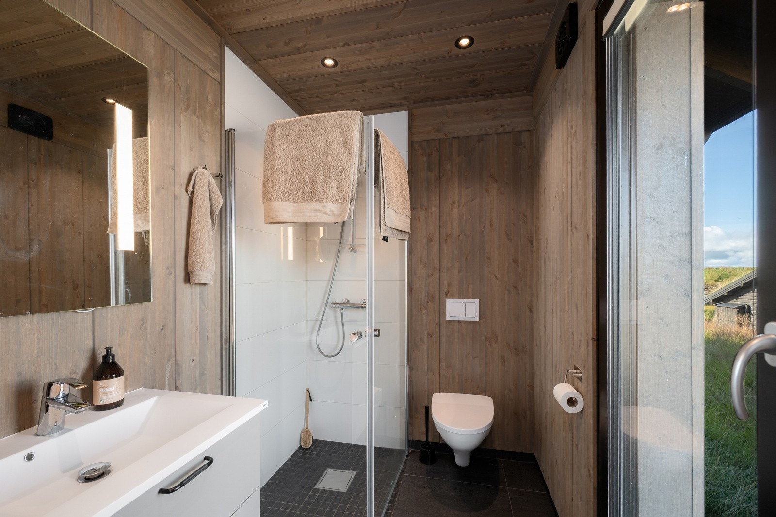 Badet er utstyrt med vegghengt toalett, dusjløsning og terrassedør. Galleribilde