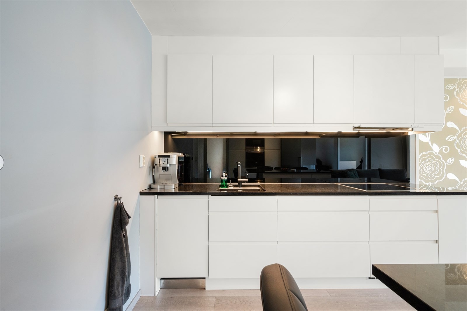 Innredningen har hvite, tidløse fronter med integrerte håndtak og benkeplate i stein som gir et stilrent uttrykk. Galleribilde