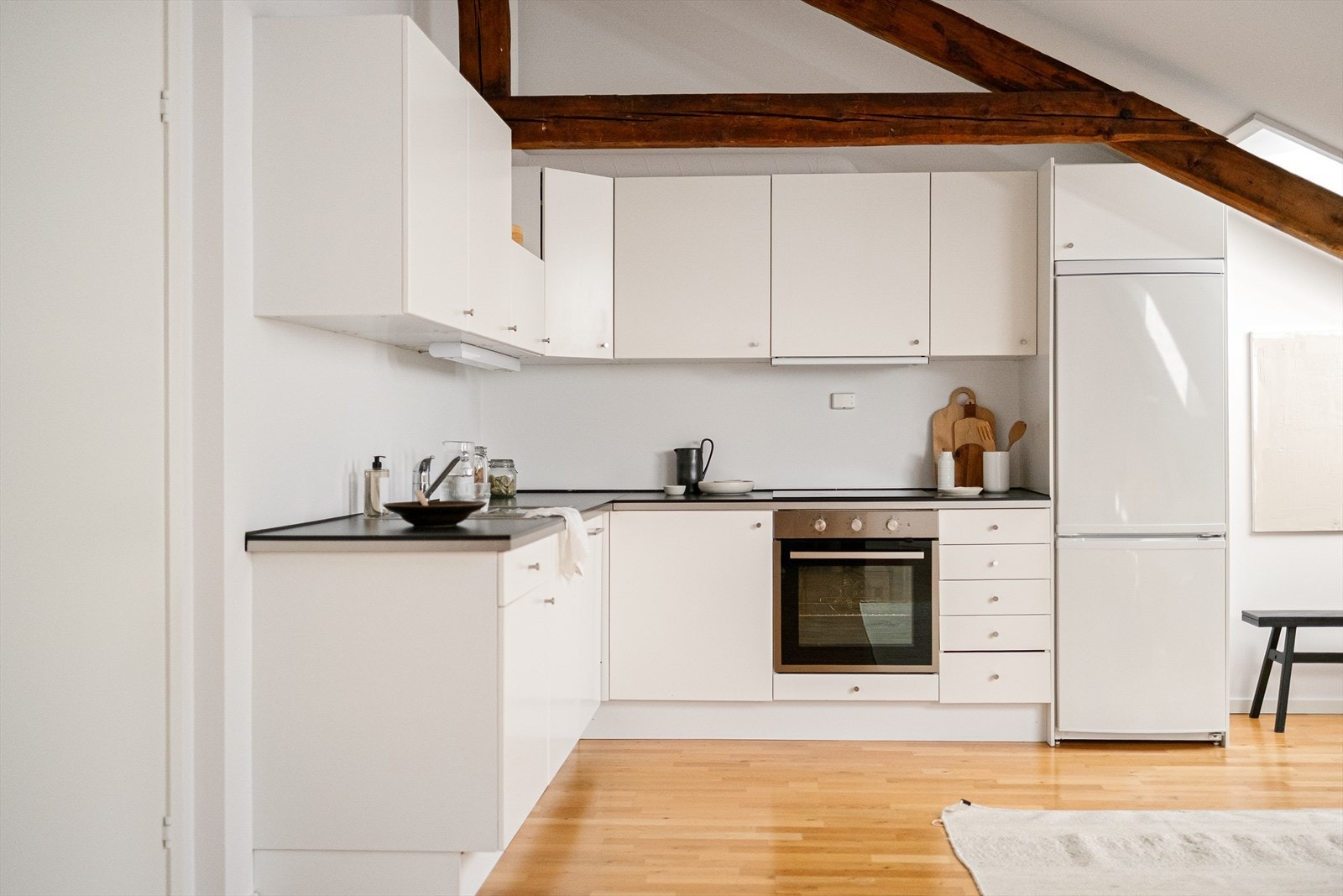 Tidsriktig glatt innredning fra IKEA, soft close, armatur, laminat benkeplate med nedfelt stålkum og keramisk topp, integrert komfyr, oppvaskmaskin, og kjøl/frys. Galleribilde