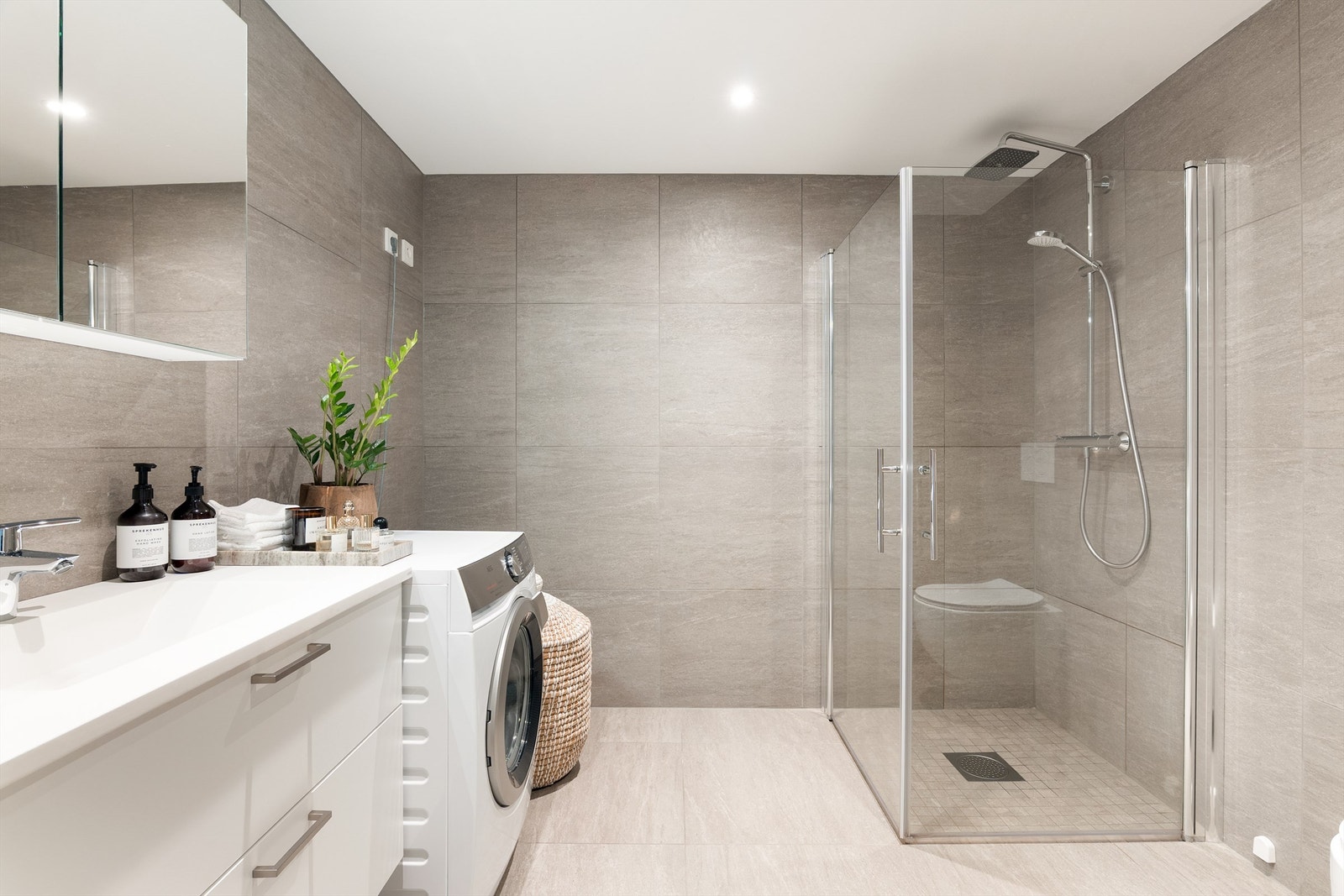 Storformat fliser på gulv og vegger gir badet helhet. Himlingens innfelte spotter kan dimmes. Galleribilde