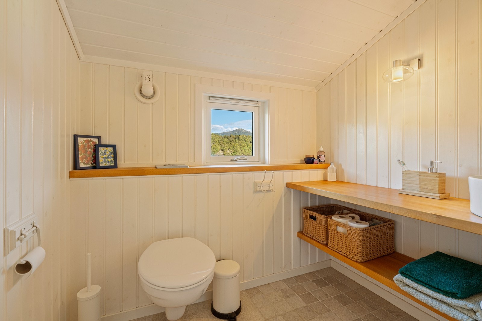 Badet har flislagt gulv med gulvvarme og veggmontert toalett. Galleribilde
