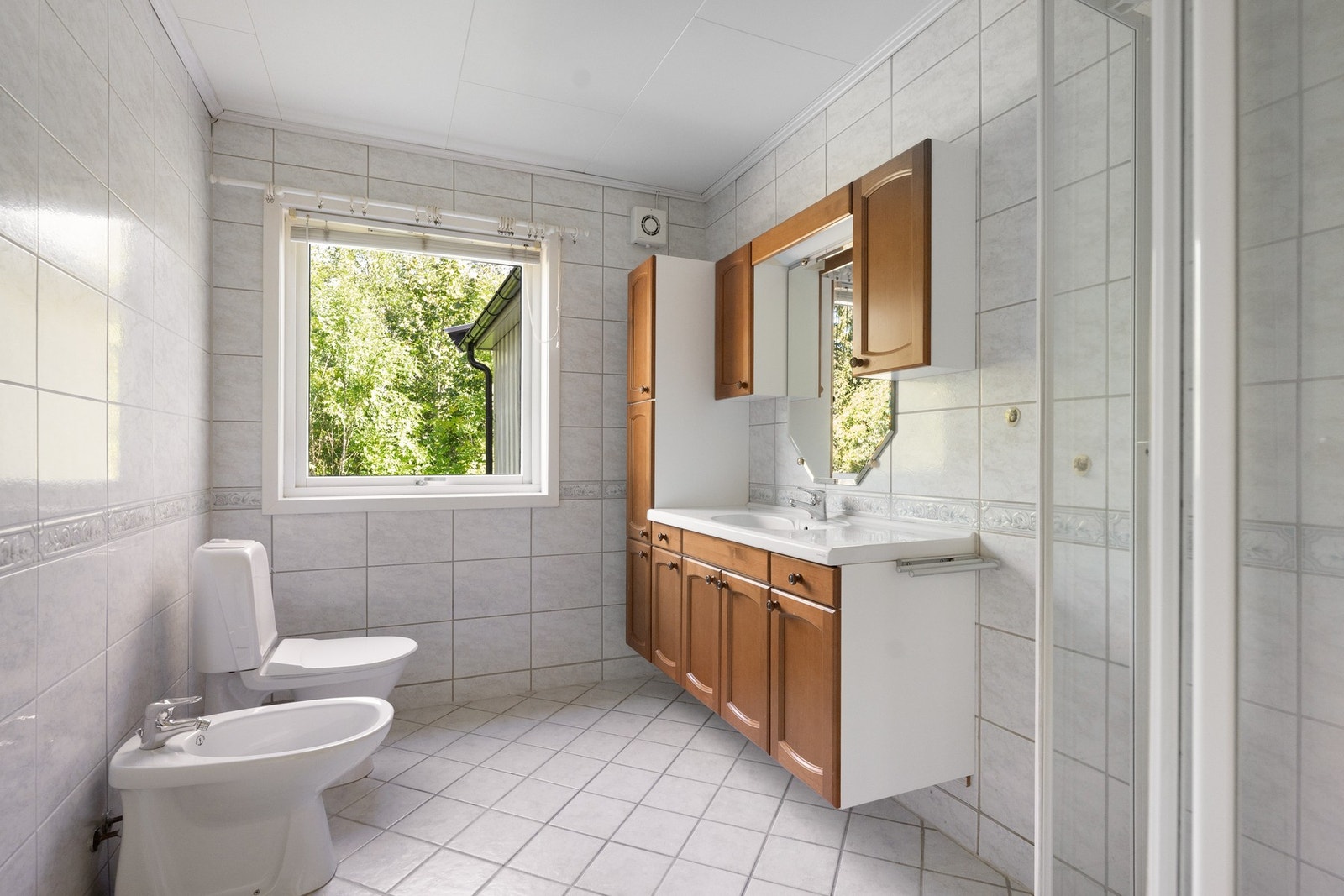 Romslig, flislagt bad med dusjhjørne, servantinnredning og vindu som gir godt med naturlig lys. Badet er byggemeldt som soverom. Galleribilde