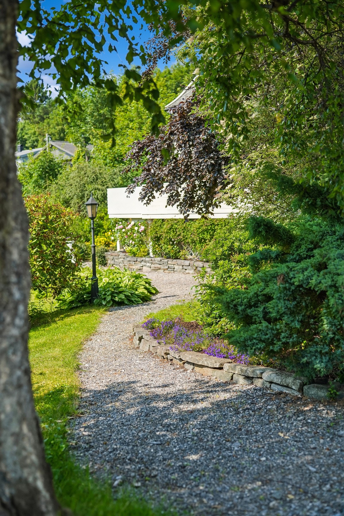Den gruslagte stien leder deg gjennom den velstelte og frodige hagen frem til boligen. Galleribilde