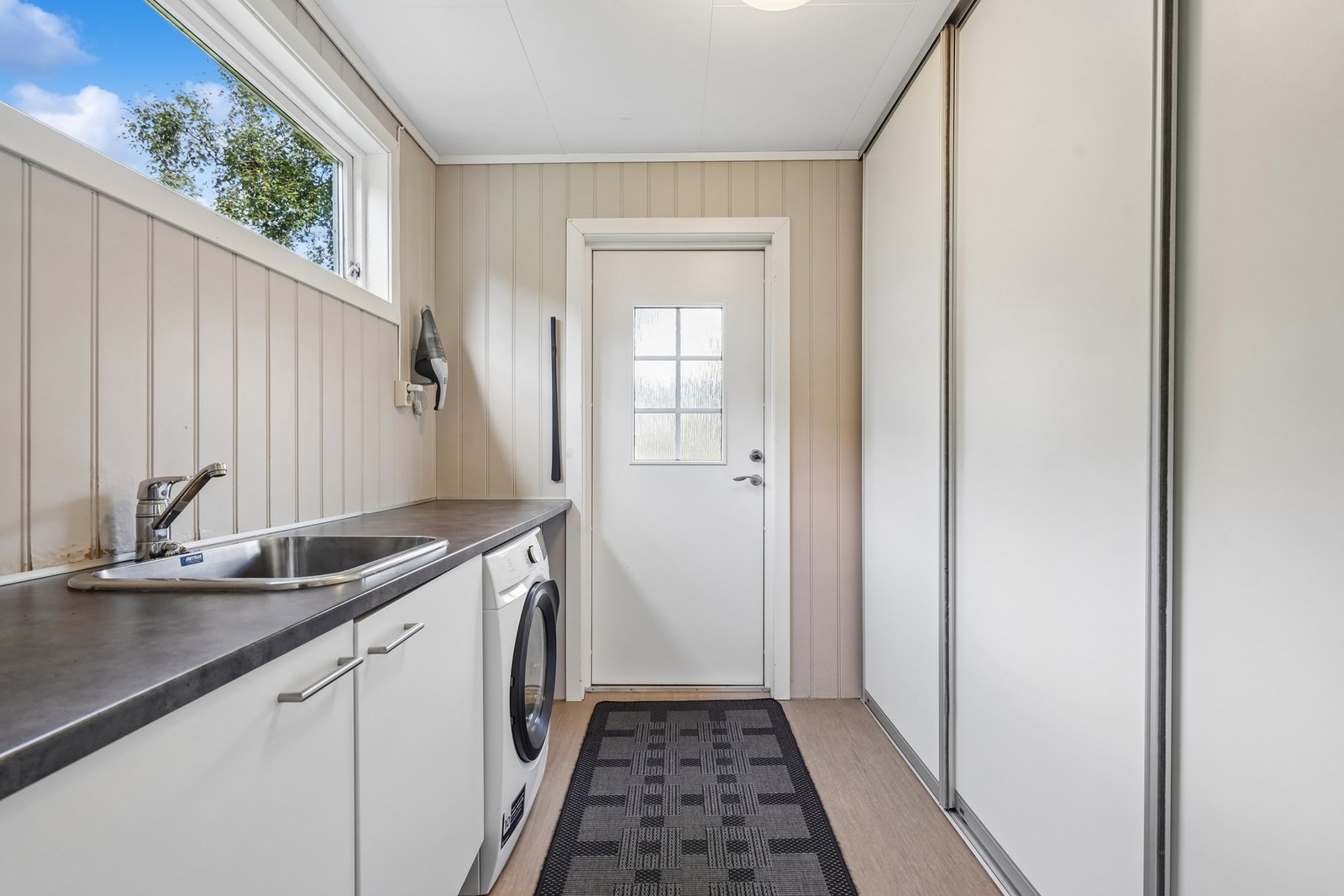 Vaskerommet fra 1981 har belegg på gulvet og MDF-panel på veggene, og er praktisk innredet med vaskeromsinnredning med utslagsvask og opplegg for vaskemaskin. Galleribilde