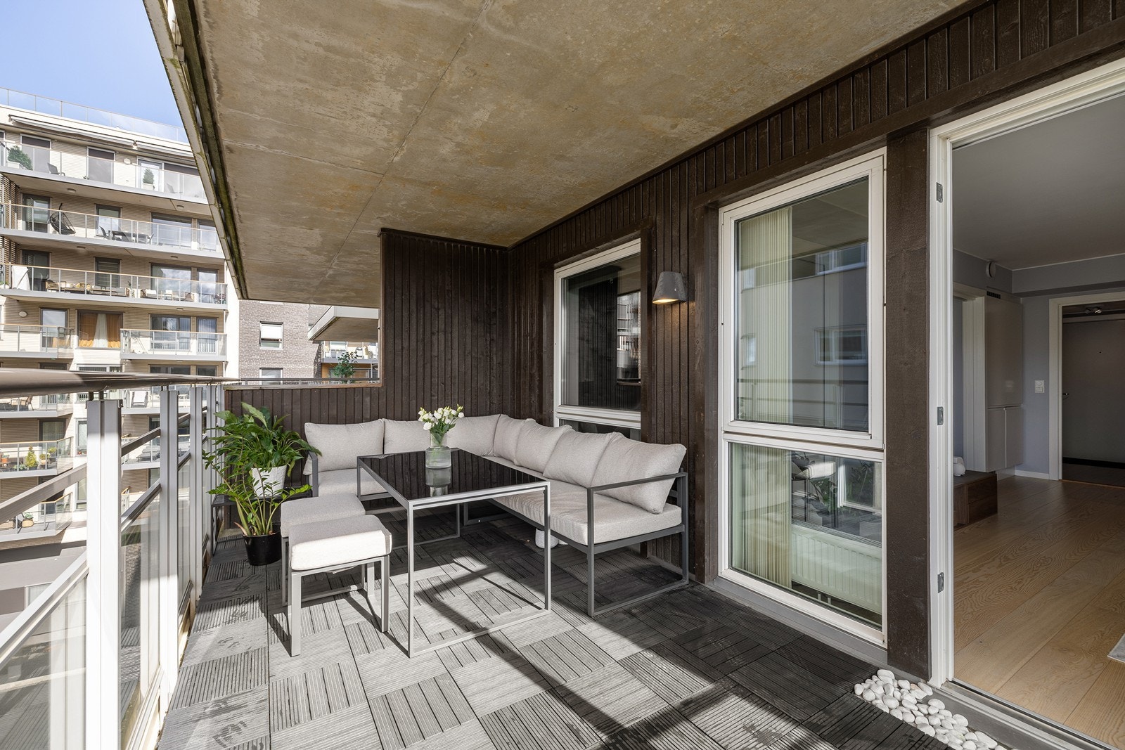 Fra stuen er det utgang til en stor og vestvendt balkong på 12 m². Uteplassen har en lun, skjermet atmosfære med mørk trekledning og praktiske terrasseheller på gulvet. Galleribilde