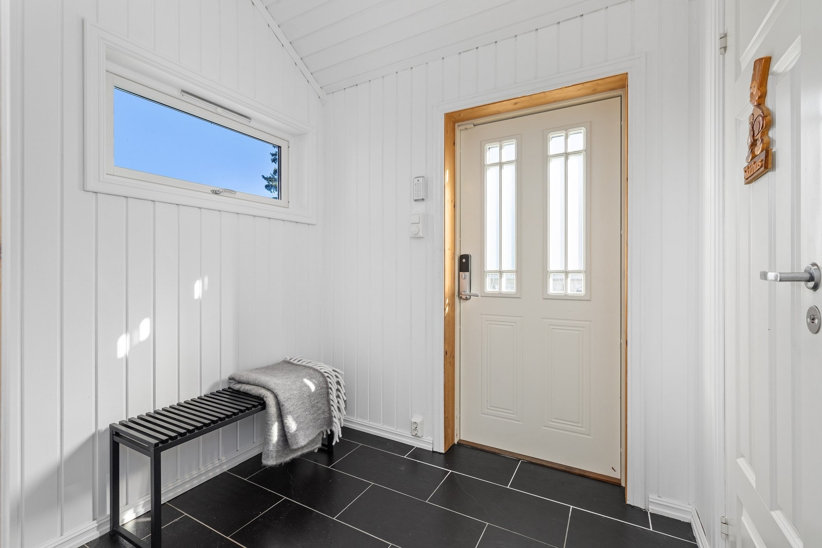 Via dør med elektronisk kodelås ønskes du velkommen inn i en entré med flislagt gulv med varme. Galleribilde