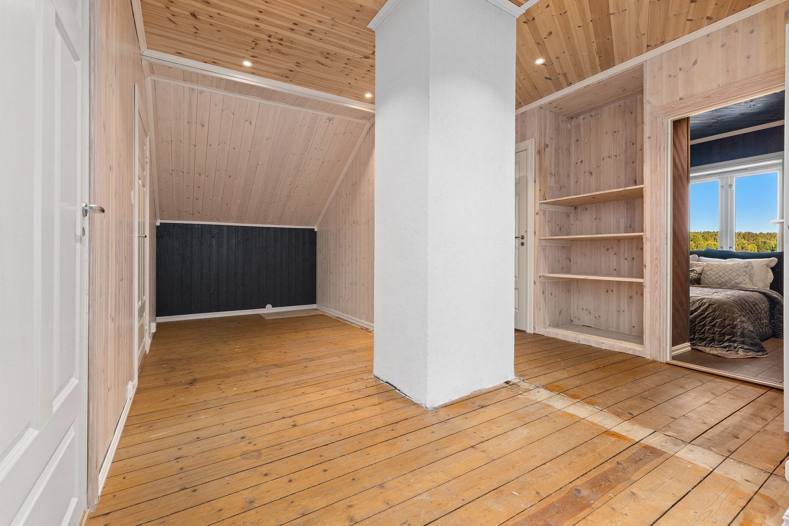 Gang i loftsetasjen med tregulv, teglsteinspipe og oppbevaringshyller. Galleribilde
